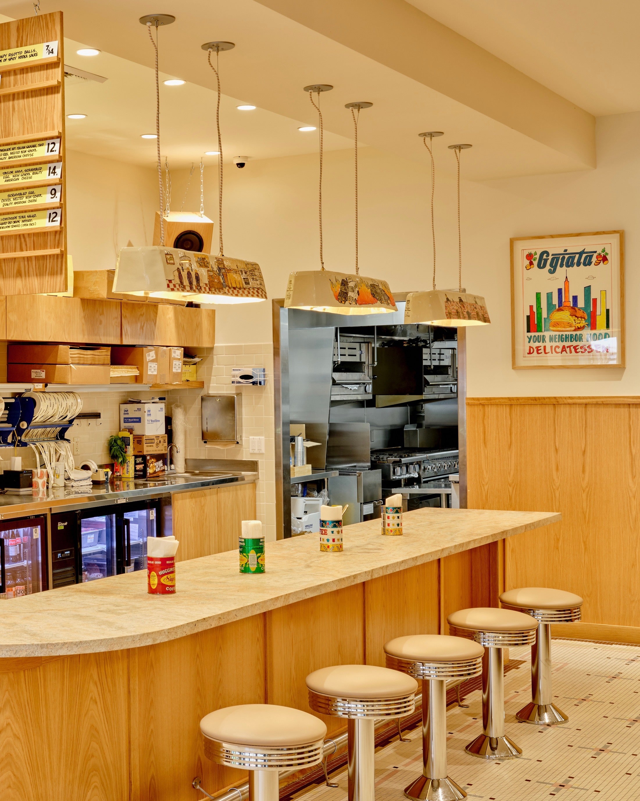 Modern cafe interior with bar stools and kitchen equipment.