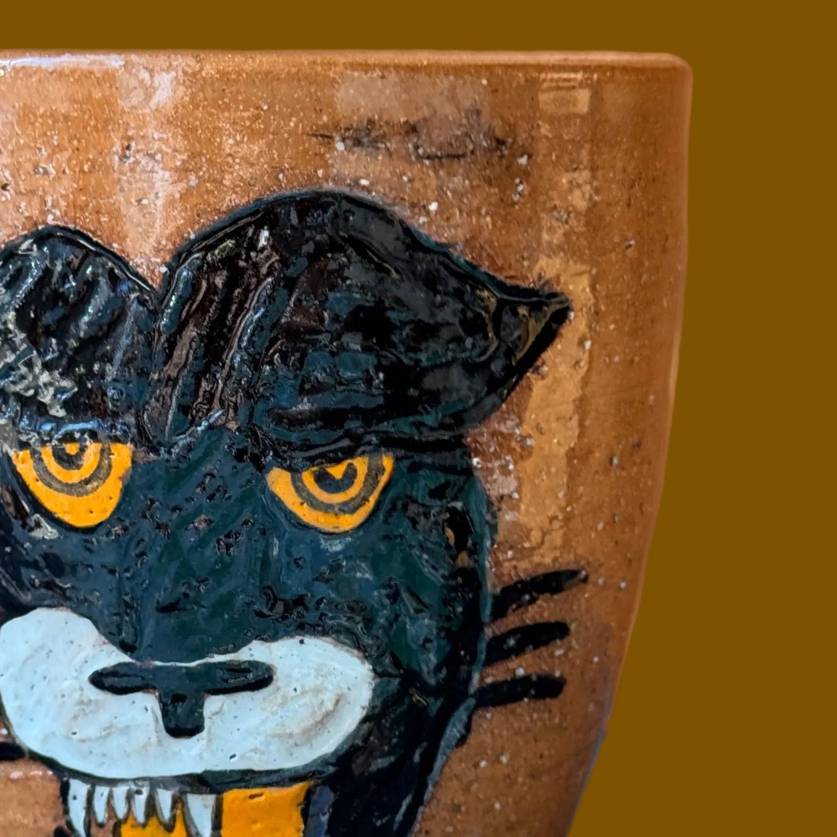 Ceramic cup with a painted panther design on a brown background